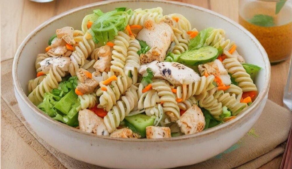 Ein frischer Nudelsalat mit zarten Hähnchenstreifen, serviert in einer weißen Schüssel und garniert mit frischen Kräutern.